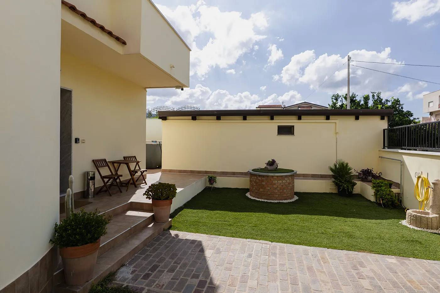 Cortile della villa con prato, tavolino con sedie e piante, Luna di Sale a Gallico (RC)